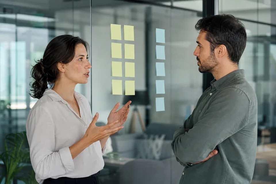 Two analysts debating in front of two columns of blank sticky notes